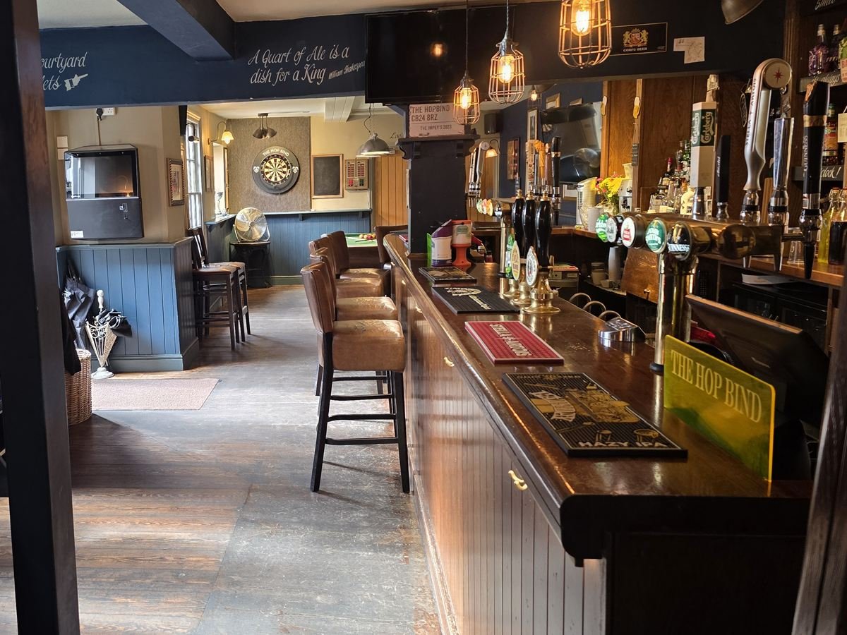 Looking along the bar with its leather bar stools and handpumps, through to the games room and dartboard