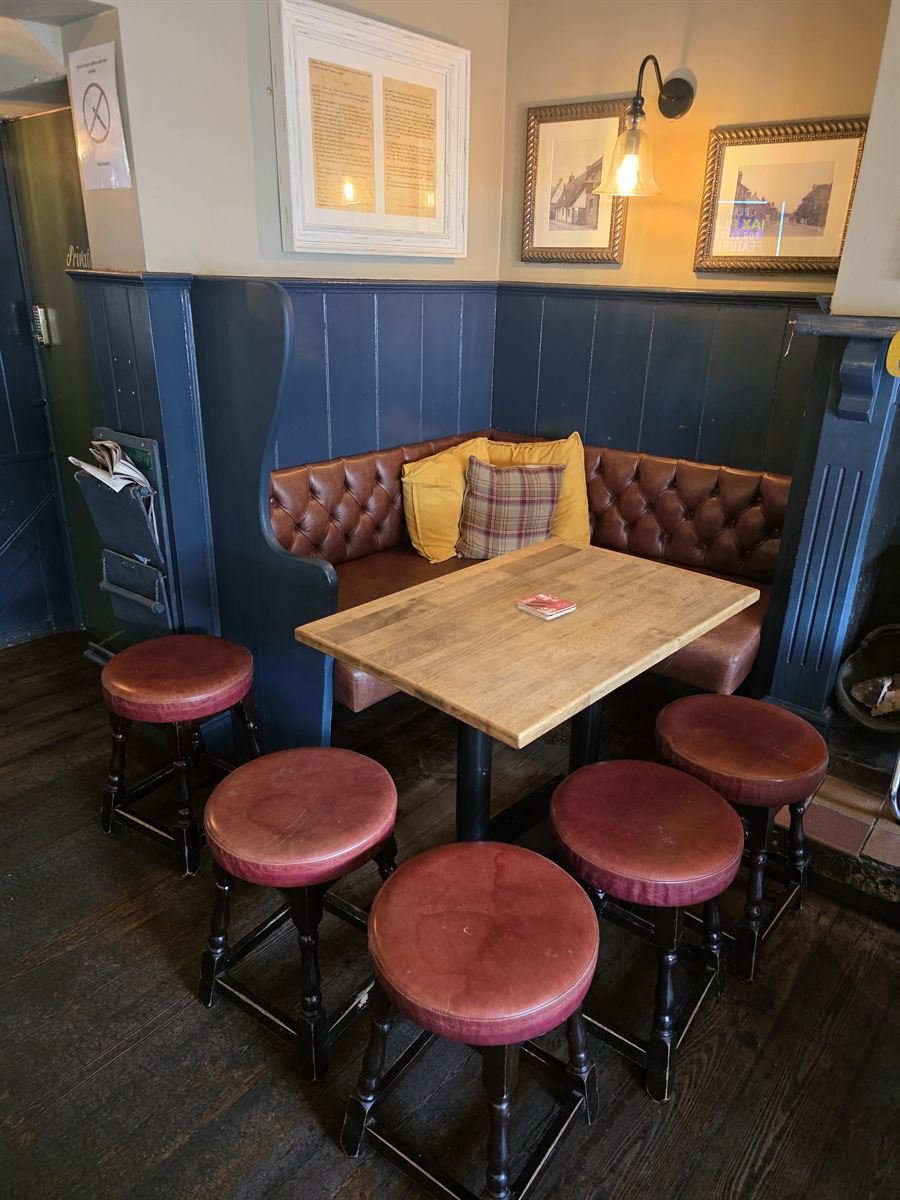 A corner booth with a tufted leather banquette, cushions and navy panelling