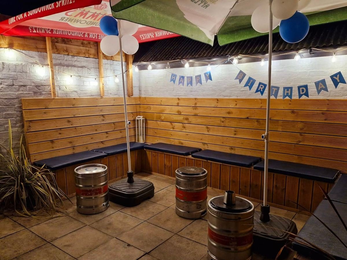 The covered courtyard seating decorated for a birthday with bunting and blue and white balloons