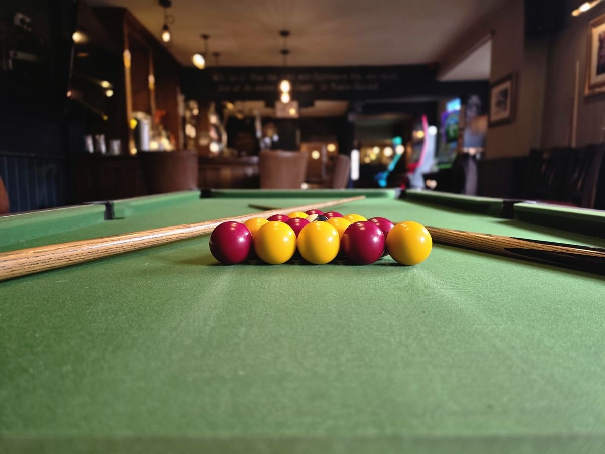 Low view across the pool table to the racked balls