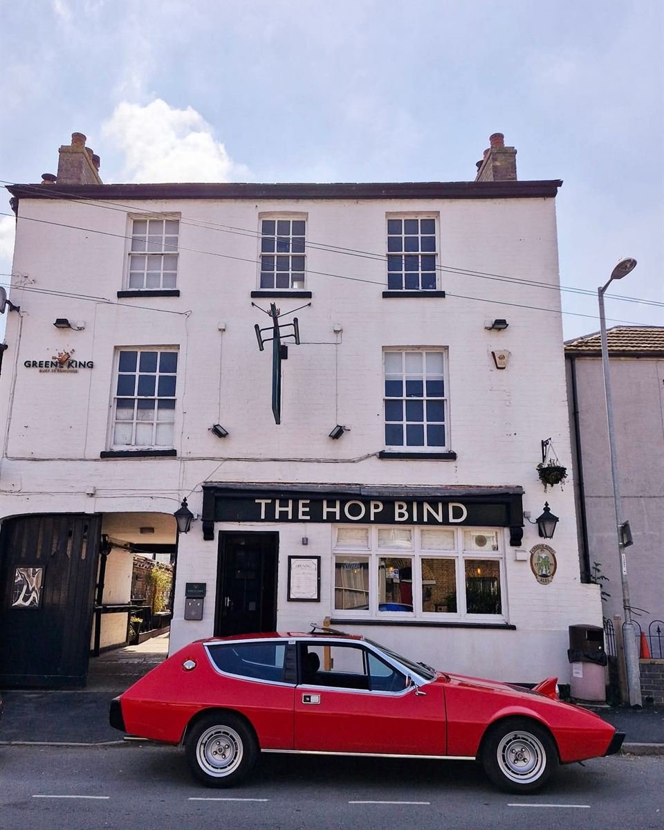 The front of The Hop Bind on the High Street: a white three-storey building with THE HOP BIND above the door and an archway on the left