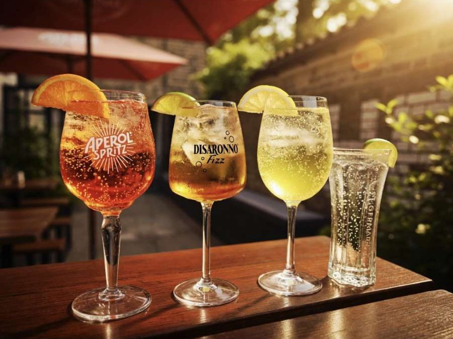 Aperol Spritz, Disaronno Fizz and Hugo spritzes in wine glasses, garnished with orange, lime and lemon