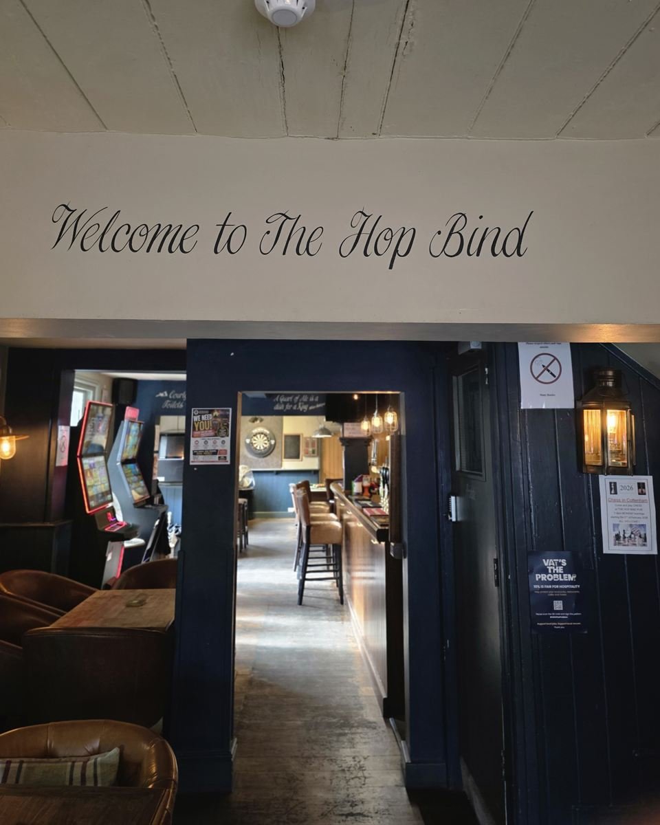 'Welcome to The Hop Bind' painted above the doorway, looking through to the bar and the dartboard beyond